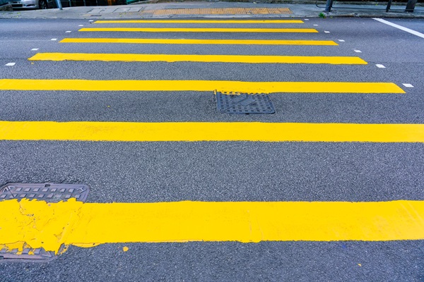 Bright yellow crosswalk lines painted across an asphalt street.