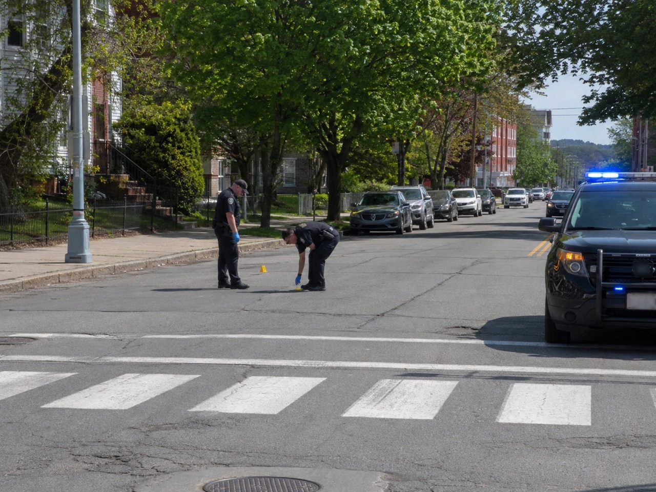 Police officers investigating a crosswalk in Maine with evidence markers on the pavement, illustrating the scene of a pedestrian hit and run and the driver's duty to remain and compensate victims.